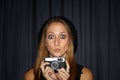 Wide-eyed style. Portrait of a young woman making a strange face and holding a vintage camera. Royalty Free Stock Photo