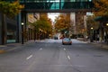 A wide four lane street downtown with cars driving surrounded by yellow autumn trees and bare winter trees