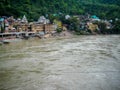 Wide ganga river having village on the other side. Brown colour ganga river in Rishikesh India