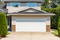 White wide garage door of residential house with concrete driveway in front