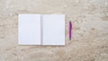Wide image of blank open notebook and purple pen placed flat on sand colored marble table surface Royalty Free Stock Photo