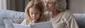 Wide image mature grandmother and little granddaughter reading book