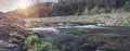 Wide image of small fast river outside of city, water flow, stone embankment.