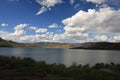 a wide lake on a grassy mountain side under a blue sky Royalty Free Stock Photo