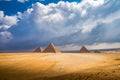 Wide landscape shot of Giza pryamids with dramatic clouds and light