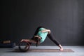 Woman doing yoga asana Wide Legged Forward Bend using special wheel.