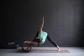 Woman doing yoga asana Wide Legged Forward Bend using special wheel.