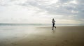 Wide lens silhouette of afro American runner woman jogging on the beach - young attractive and athletic black girl training Royalty Free Stock Photo