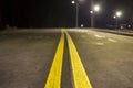 Wide modern smooth empty illuminated with street lamps asphalt highway with bright white marking sign line at night. Speed, safety Royalty Free Stock Photo