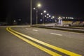 Wide modern smooth empty illuminated with street lamps asphalt highway with bright white marking sign line at night. Speed, safety Royalty Free Stock Photo