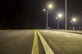 Wide modern smooth empty illuminated with street lamps asphalt highway with bright white marking sign line at night. Speed, safety Royalty Free Stock Photo