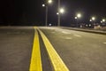 Wide modern smooth empty illuminated with street lamps asphalt highway with bright white marking sign line at night. Speed, safety Royalty Free Stock Photo