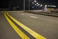 Wide modern smooth empty illuminated with street lamps asphalt highway with bright white marking sign line at night. Speed, safety Royalty Free Stock Photo