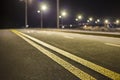 Wide modern smooth empty illuminated with street lamps asphalt highway with bright white marking sign line at night. Speed, safety Royalty Free Stock Photo