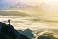 Wide mountain panorama. Small silhouette of tourist with backpack on rocky mountain slope with raised hands over valley covered