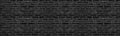 Wide old black brick wall texture. Dark rough masonry panorama. Brickwork panoramic grunge background Royalty Free Stock Photo