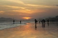 Wide open beach on the sunset with people silhouettes and orange sky. Royalty Free Stock Photo