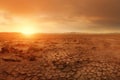 Wide panorama of barren cracked land with sun barely visible through the dust storm