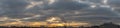 Wide panorama of cloudy sunrise or sunset over rooftops Royalty Free Stock Photo