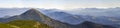 Wide panorama of green mountain hills in sunny clear weather. Carpathian mountains landscape in summer. View of rocky peaks covere Royalty Free Stock Photo