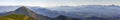 Wide panorama of green mountain hills in sunny clear weather. Carpathian mountains landscape in summer. View of rocky peaks covere