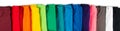 Wide panorama row of many fresh new fabric cotton t-shirts in colorful rainbow colors isolated. Pile of various colored shirts