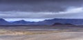 Wide panoramic shot of rough volcanic landscape of Iceland under very heavy and dramatic clouds. No vegetation. Lava and