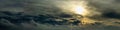 wide panoramic view of a dark dramatic sky with gray clouds and back sunlight through atmospheric haze Royalty Free Stock Photo