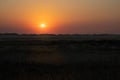 Wide panoramic view over the grassland between the dike and the beach against the deep setting sun. Royalty Free Stock Photo