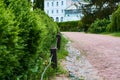 Wide path of crushed stone in green garden, park in spring with bushes fences. Royalty Free Stock Photo