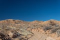 Wide path through the New Mexico desert leading up to a ridge before blue sky, road less traveled