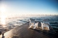 Wide photo of Muskoka Chairs on a dock with sun rising and mist