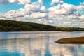 Wide quiet deep river flowing into the distance with sandy and hilly coasts covered with forest sunny with day and white clouds Royalty Free Stock Photo