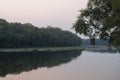 Wide river flowing across green forest. Fall. Evening. Reflections of trees in the calm water. Sundown Royalty Free Stock Photo