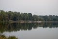 Wide river flowing across green forest. Fall. Evening. Reflections of trees in the calm water. Sundown Royalty Free Stock Photo