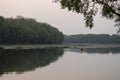 Wide river flowing across green forest. Fall. Evening. Reflections of trees in the calm water. Sundown Royalty Free Stock Photo