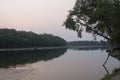 Wide river flowing across green forest. Fall. Evening. Reflections of trees in the calm water. Sundown Royalty Free Stock Photo