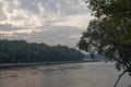 Wide river flowing across green forest. Fall. Evening. Reflections of trees in the calm water. Sundown Royalty Free Stock Photo