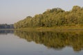 Wide river flowing across green forest. Fall. Morning Reflections in the water Royalty Free Stock Photo