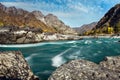 Wide river flows along stony banks among rocky mountains against clear blue sky. Turquoise water of stormy river and huge stones. Royalty Free Stock Photo