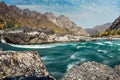 Wide river flows along stony banks among rocky mountains against clear blue sky. Turquoise water of stormy river and huge stones. Royalty Free Stock Photo