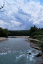 Wide river among mountains of gorge and green vegetation around. Stormy mountain river with bluish tinge from sky flows quickly Royalty Free Stock Photo