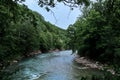 Wide river among mountains of gorge and green vegetation around. Stormy mountain river with bluish tinge from sky flows quickly Royalty Free Stock Photo