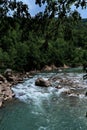 Wide river among mountains of gorge and green vegetation around. Stormy mountain river with bluish tinge from sky flows quickly Royalty Free Stock Photo