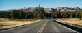 A wide road for cars with yellow markings leads to forest and mountains. Panorama view Royalty Free Stock Photo