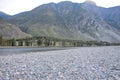 A wide rocky bank of a stormy river at the foot of a high mountain on a summer evening Royalty Free Stock Photo