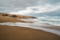 Wide sandy beach, birds, sand dunes, stormy ocean, and cloudy sky background Royalty Free Stock Photo