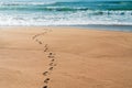 Wide sandy beach and foot prints on sand, turquoise colored sea waves on background. Royalty Free Stock Photo