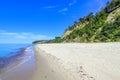 A wide sandy beach near a high sandy cliff near the blue sea