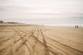 Wide sandy beach, tire tracks, and silhouettes of walking people. Pacific ocean and cloudy sky on the background. Oceano, Royalty Free Stock Photo